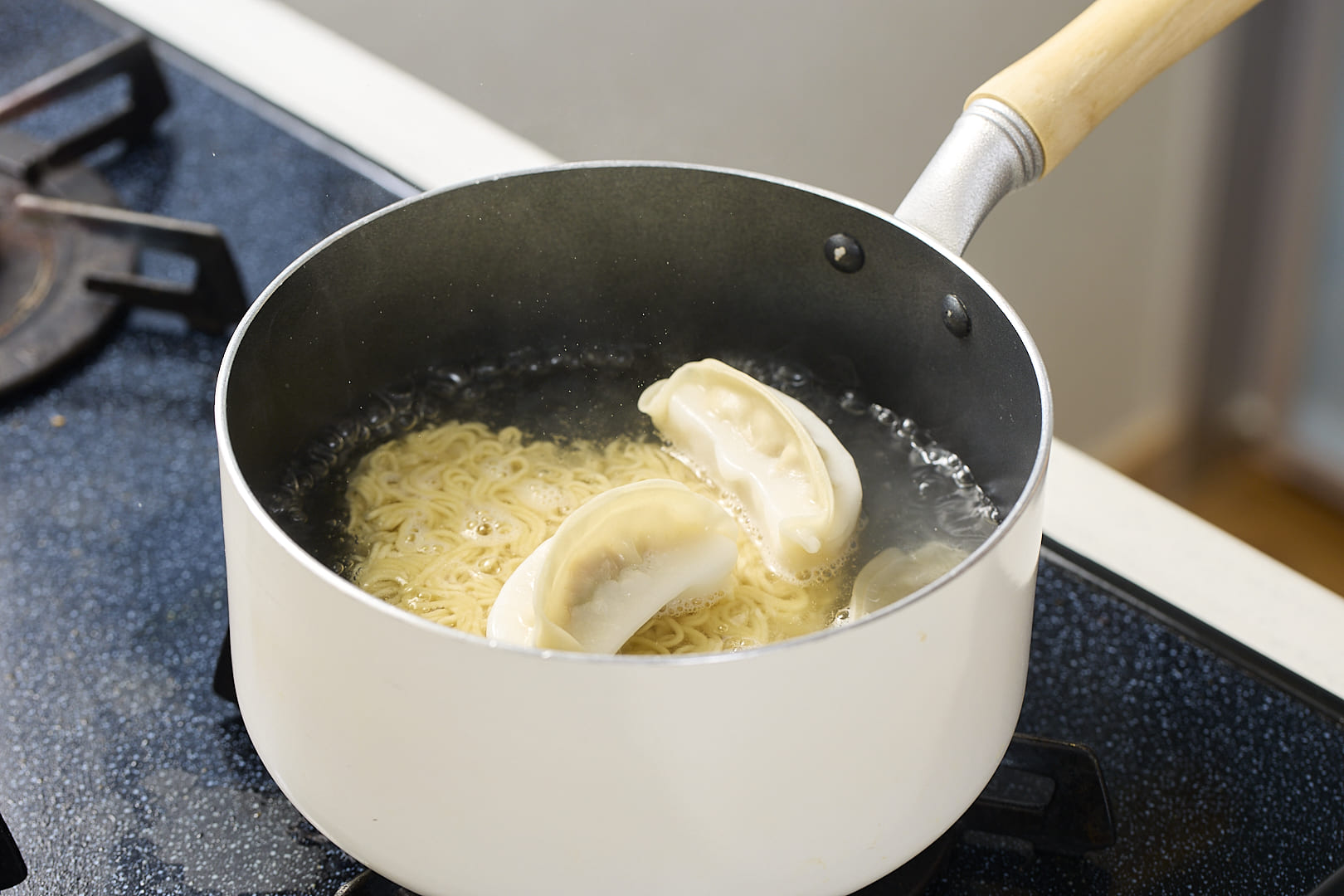 鍋に水を入れて沸騰させ、インスタントラーメンの麺、羽根つき餃子を加えたら、袋の表示時間-1分茹でる。