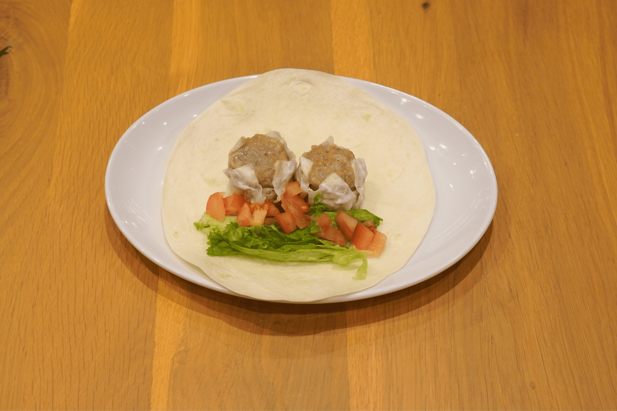 トルティーヤの中央にたれつき肉焼売・レタス・トマトをのせる。