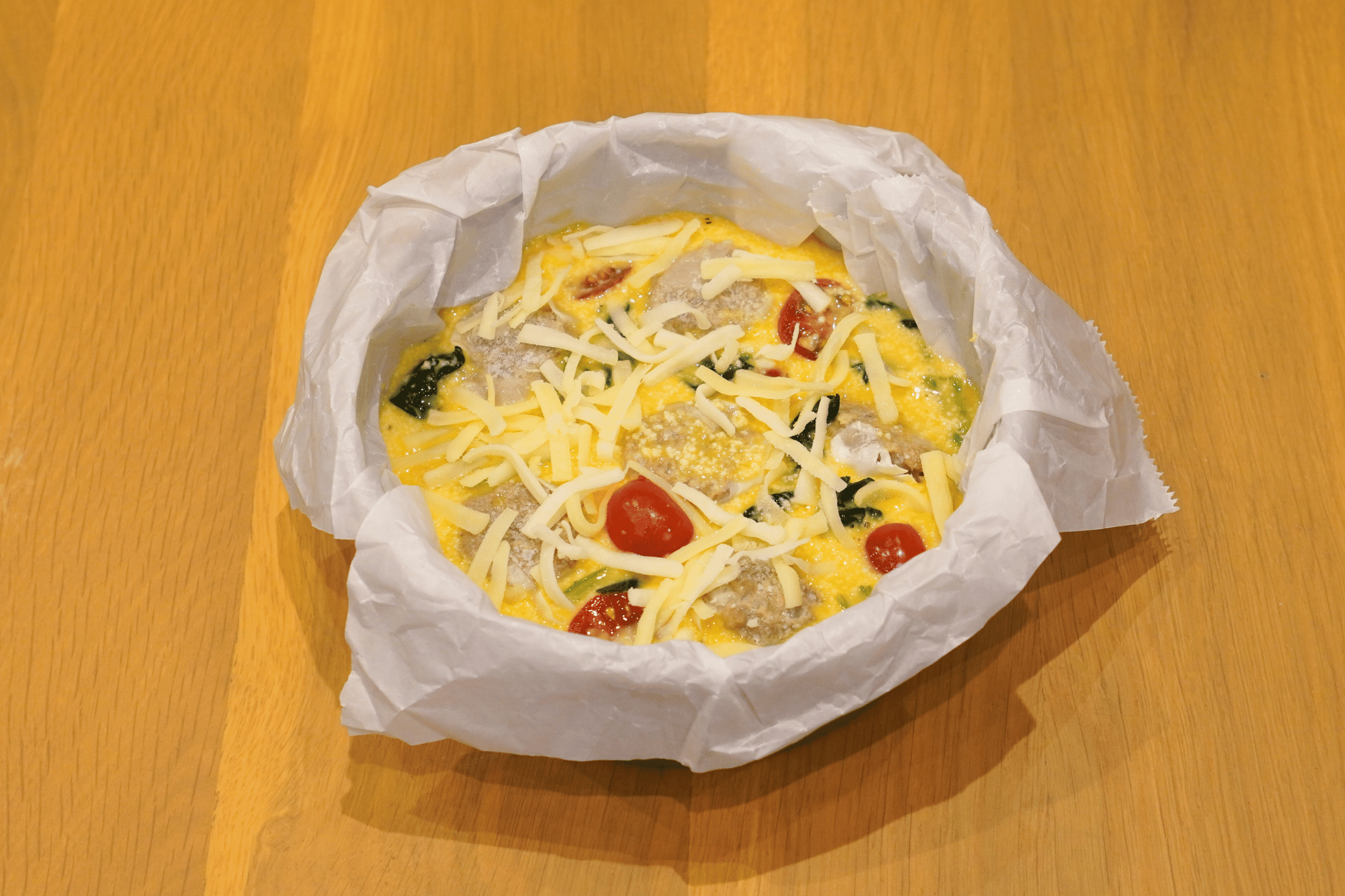 卵・牛乳・粉チーズ・黒胡椒を混ぜて容器に流し入れ、チーズをかける。